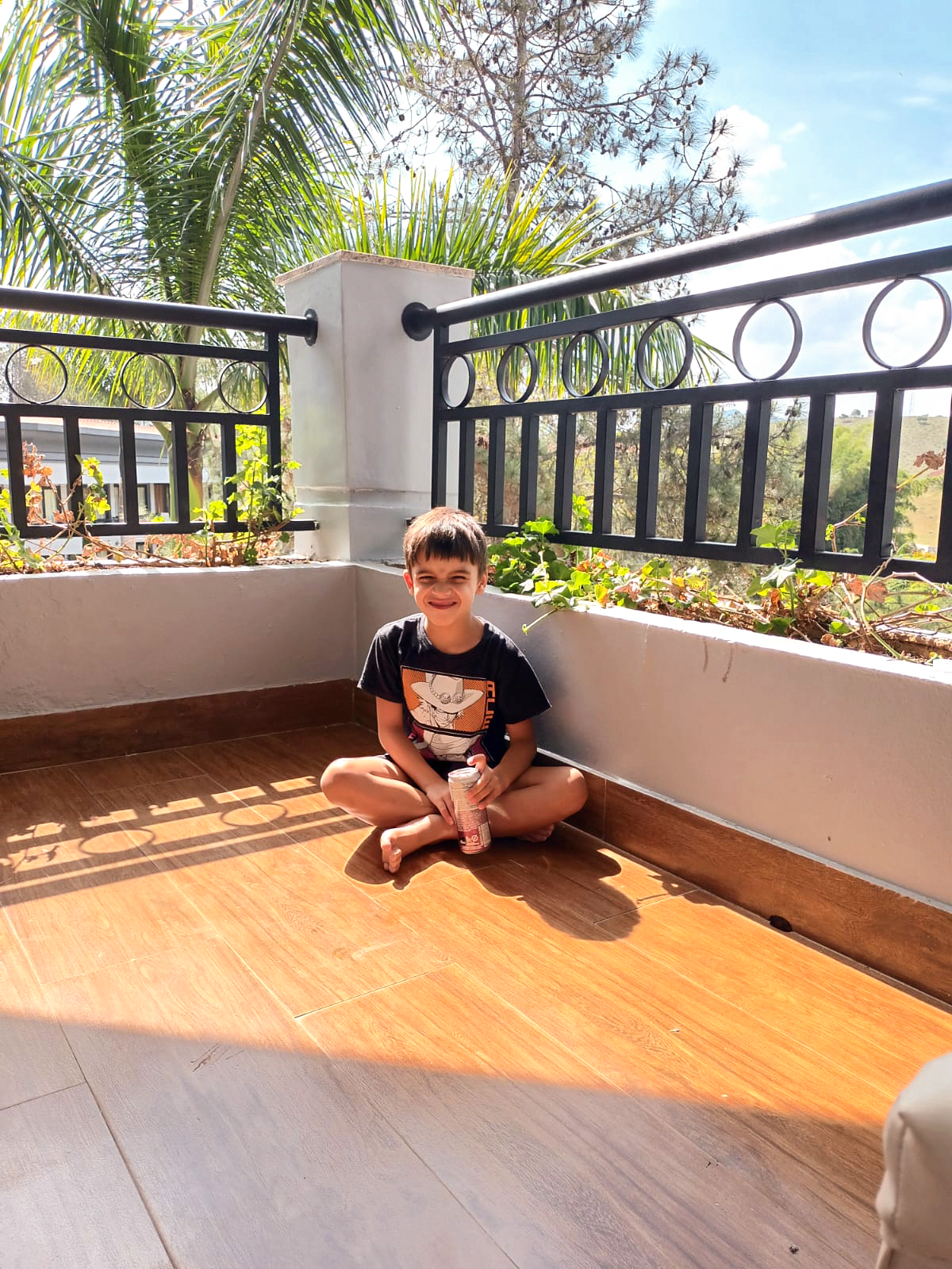 Thales sentado no canto de uma varanda com o sol refletindo em seu rosto